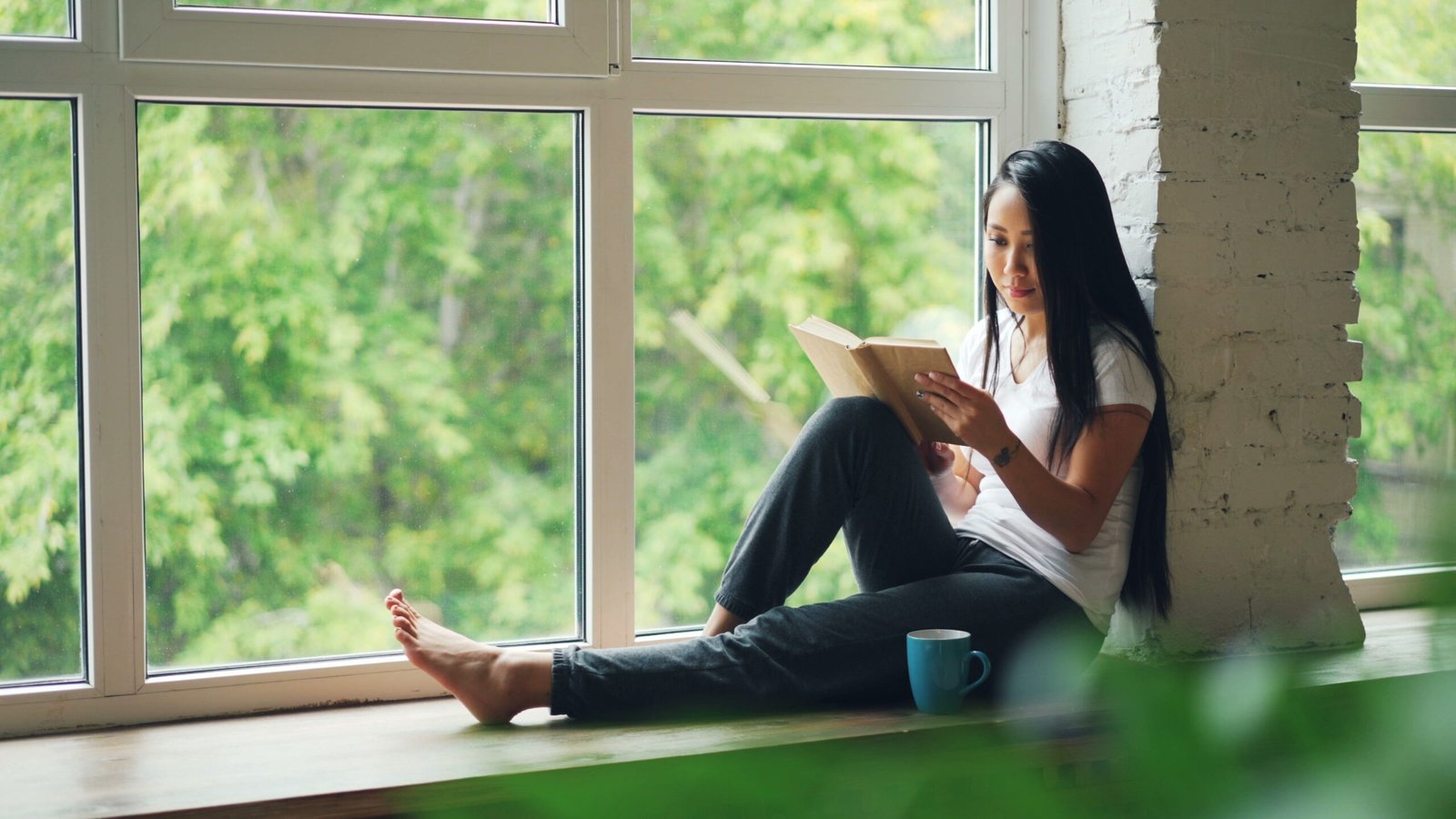 A young woman reading peacefully in a calm environment, representing emotional stabilization at Restoration Recovery Residence